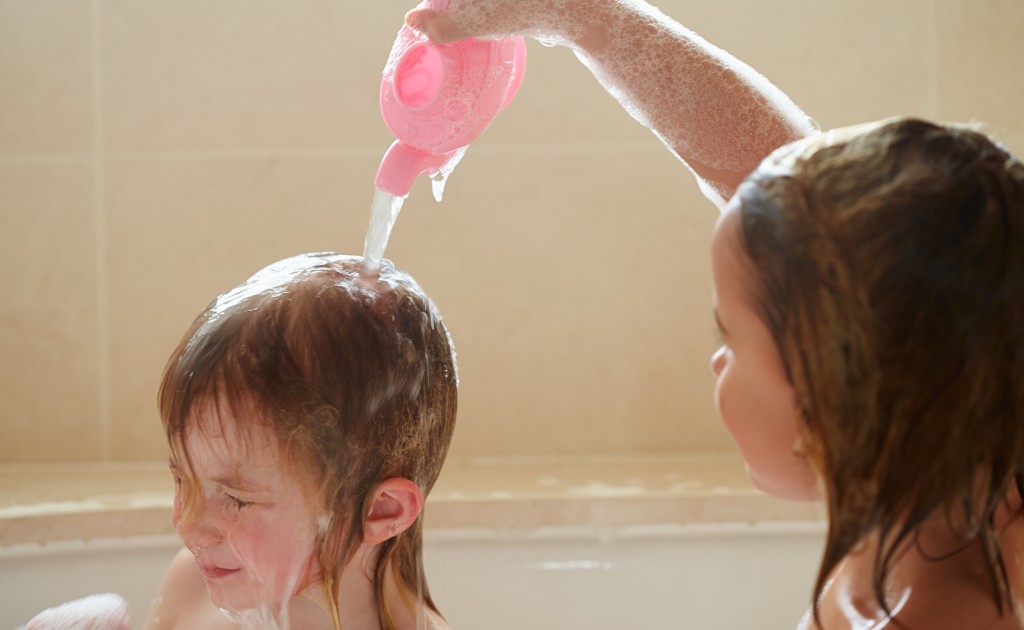 Crianças lavando o cabelo durante banho em família