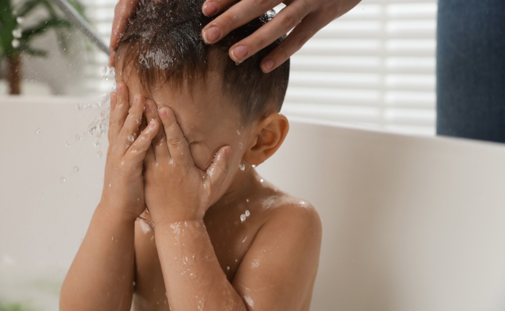 Cabelo infantil sendo enxaguado com cuidado no banho