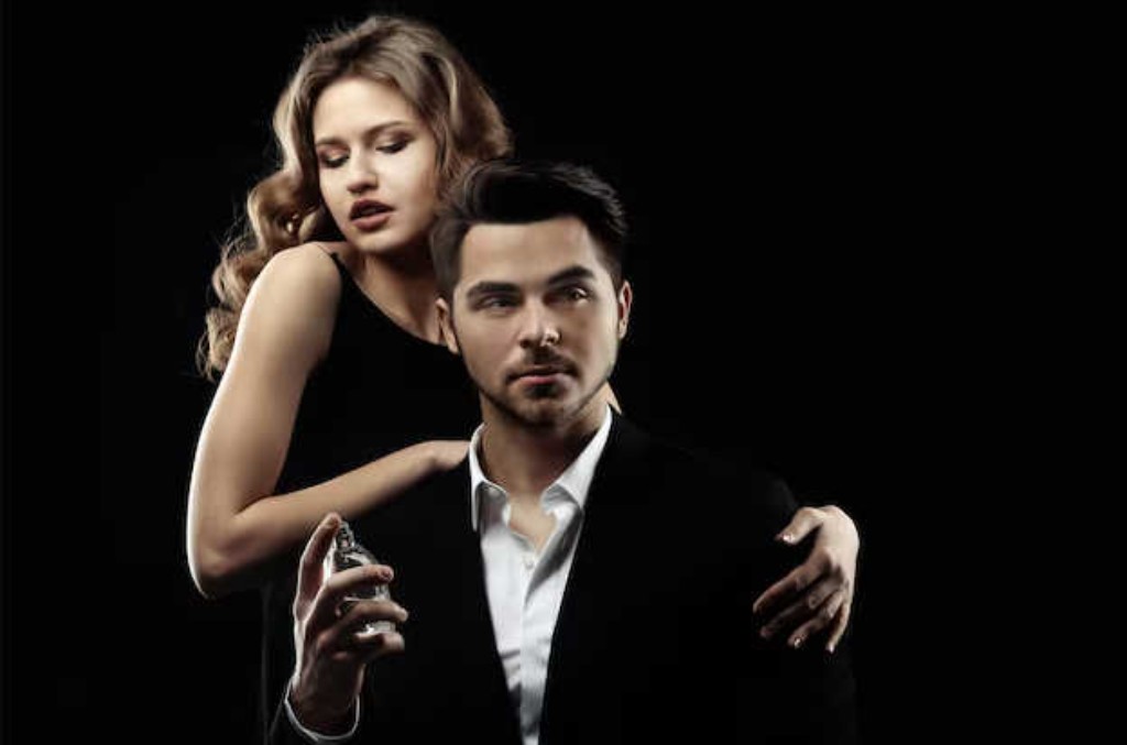 Mulher segurando frasco de perfume ao lado de homem elegante de terno