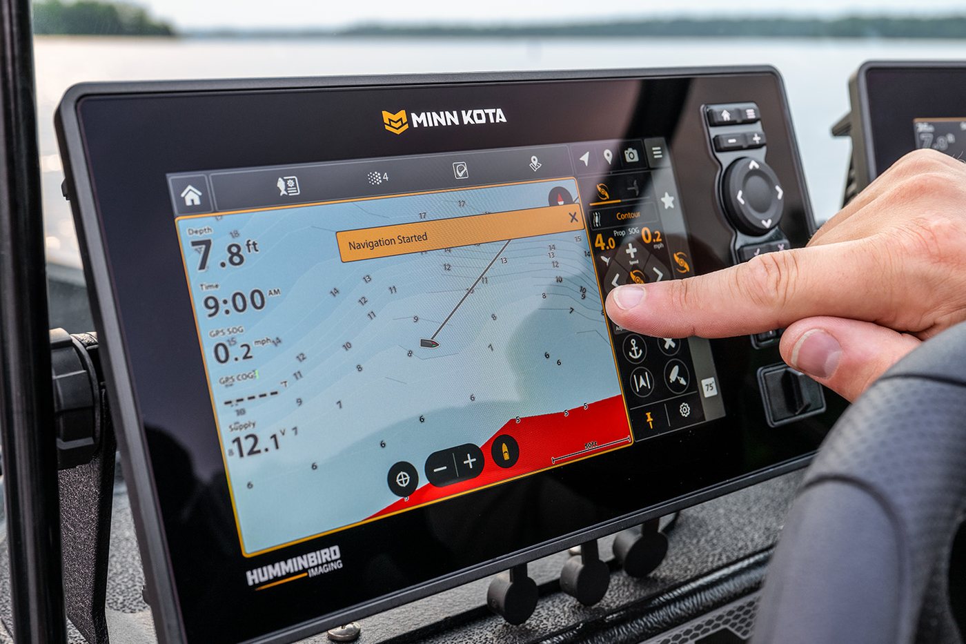 Mão no teclado Cross Touch do sonar Minn Kota X Series com o mapa na tela, dentro do barco