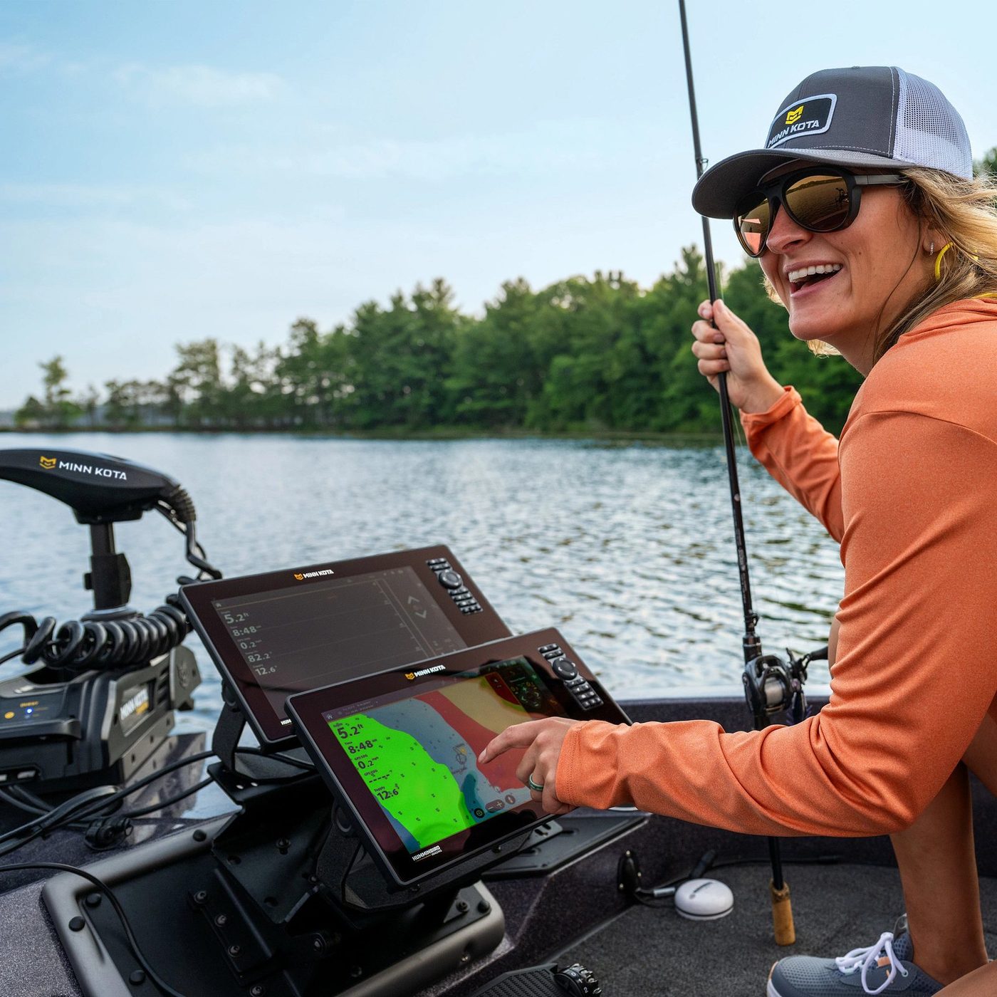 Pescadora sorrindo ao lado do sonar Minn Kota X Series em um lago