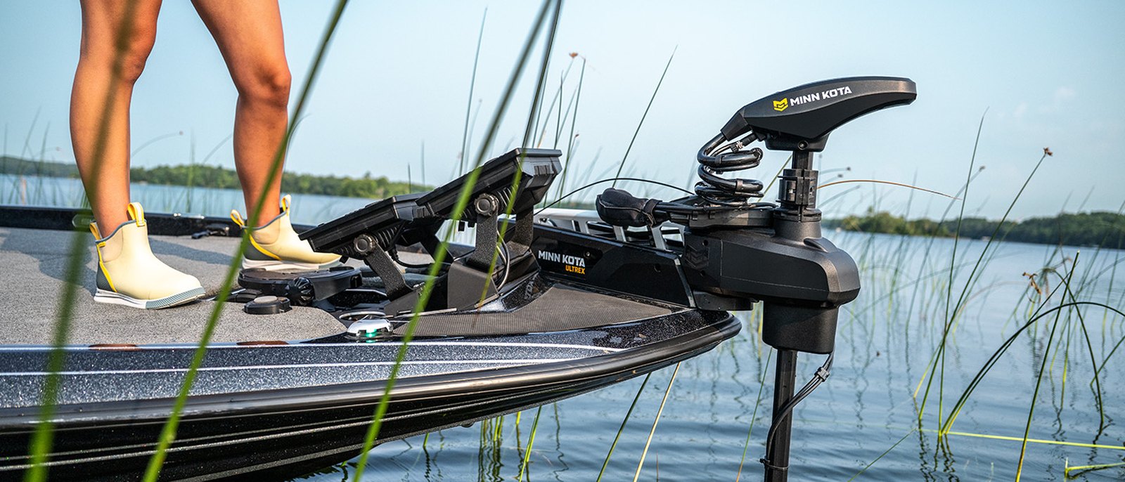 Motor elétrico Minn Kota baixado na proa do barco, trabalhando no meio da vegetação