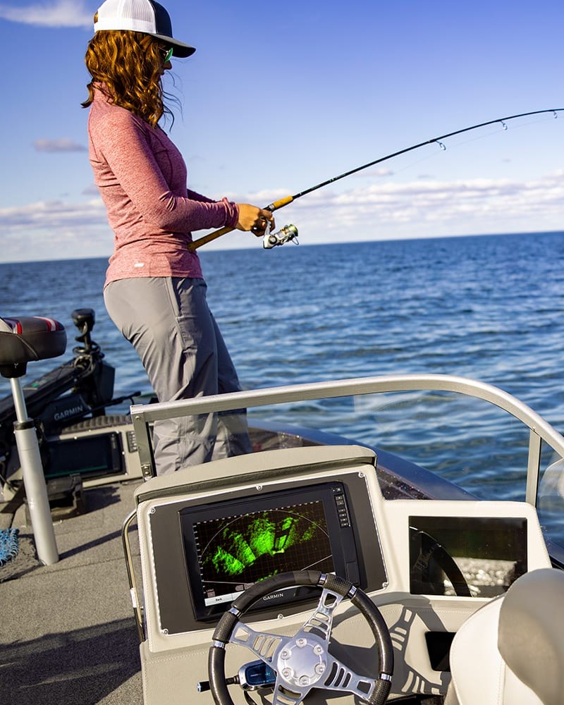 Pescadora arremessando na proa de um barco costeiro, com o sonar Garmin mostrando a imagem ao vivo do LiveScope XR