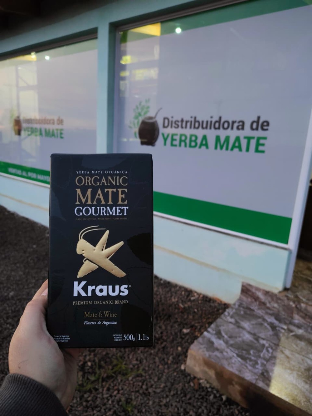 Paquete de Kraus - Yerba Mate Orgánica Gourmet 500 Gr, de fondo el local comercial de la Distribuidora de Yerba Mate en Los Helechos - Misiones.