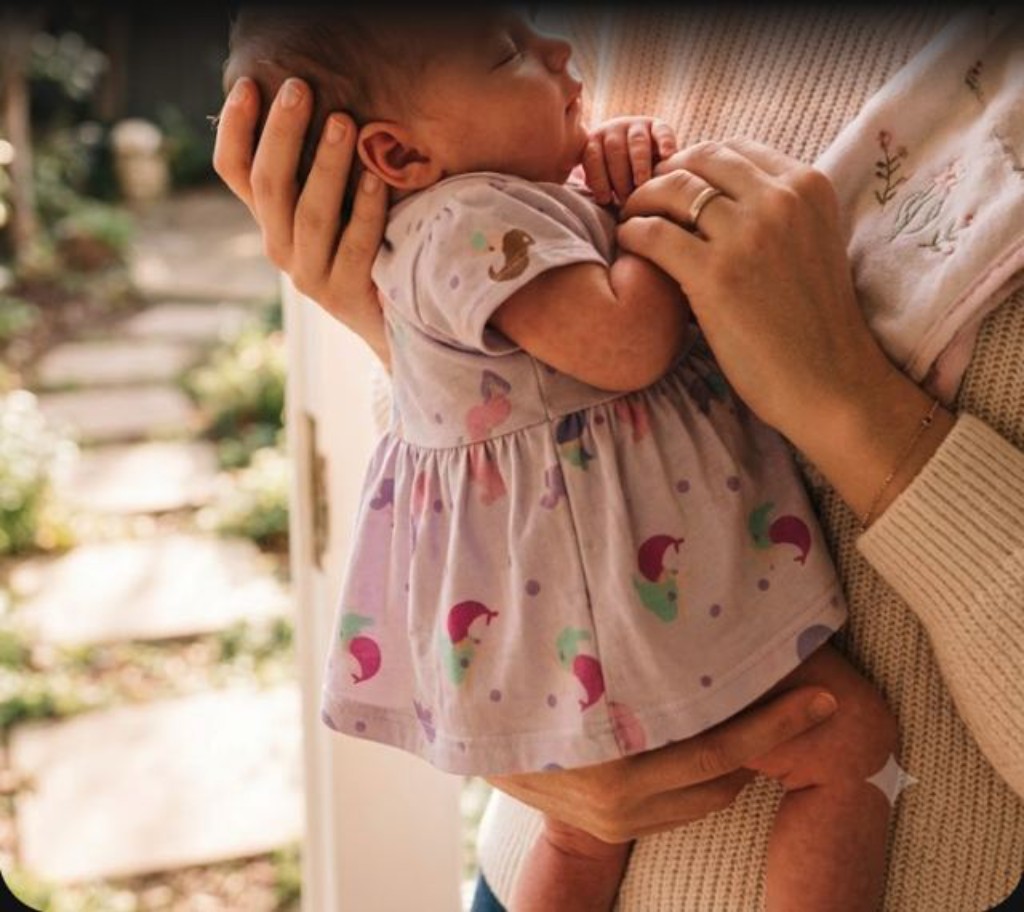 Beb&ecirc; vestindo vestido body cotton estampa de sereia lil&aacute;s no colo da m&atilde;e