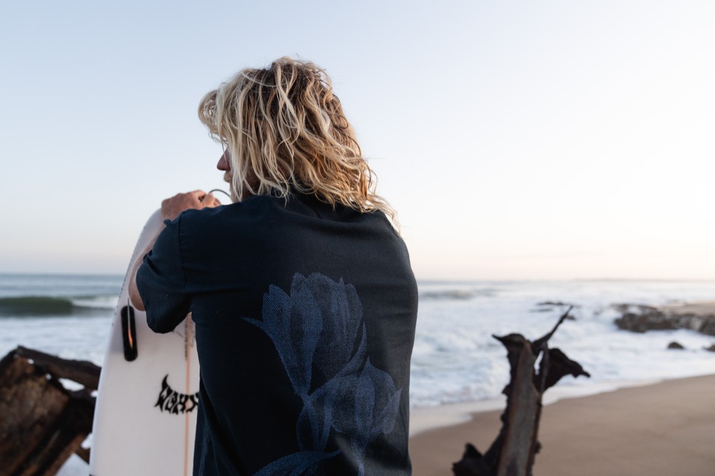 Chuck mirando el mar con su tabla al atardecer en La Pedrera