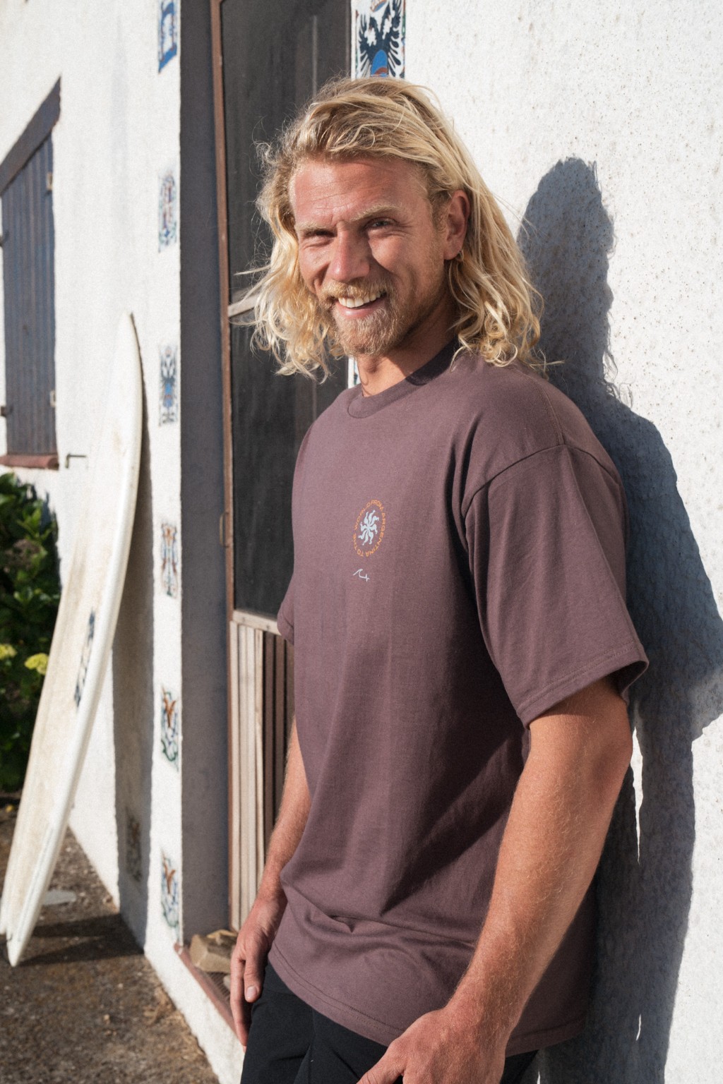 Chuck con remera vinotinto de Underwave apoyado en una casa de La Pedrera