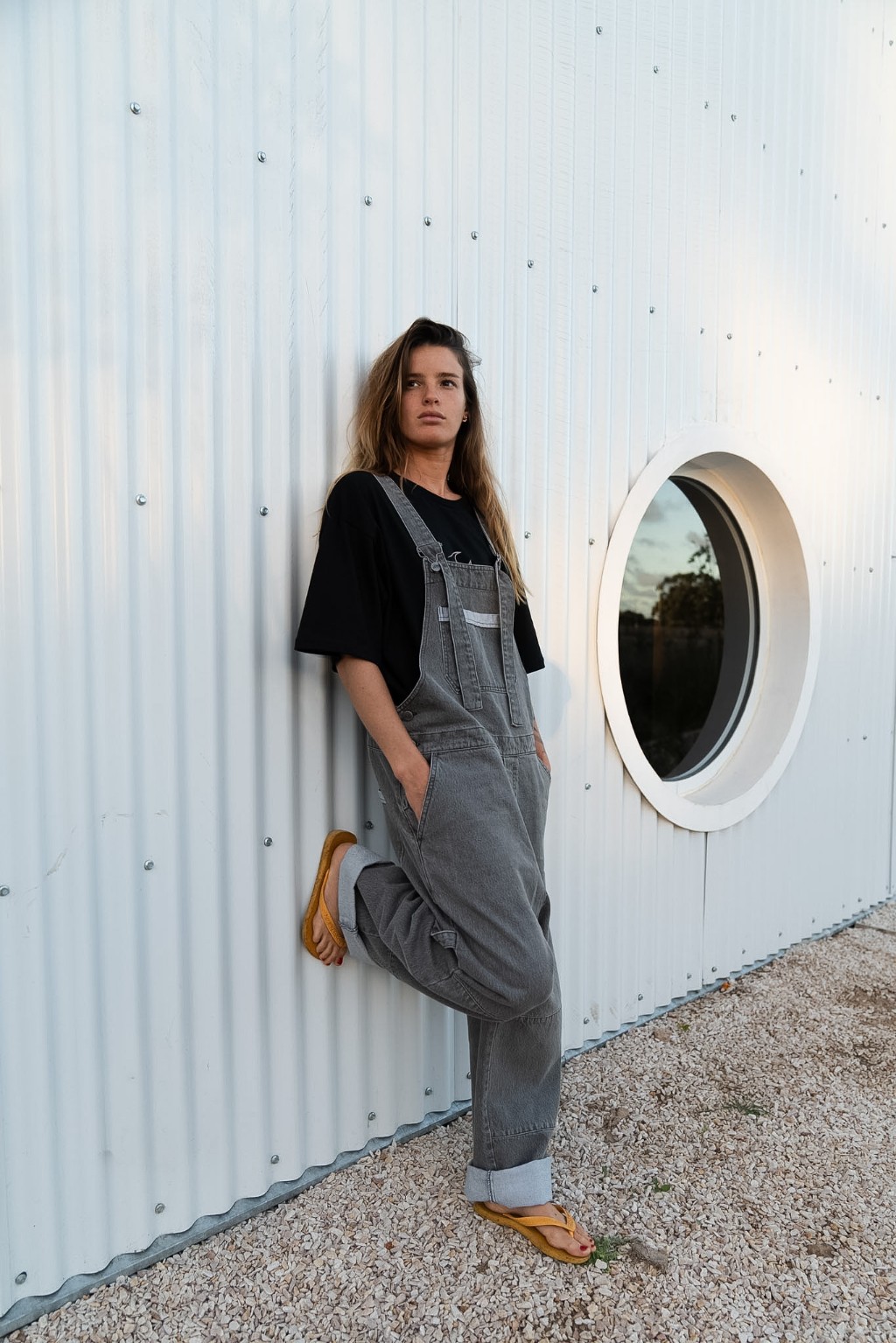 Chica con jardinero de jean de Underwave apoyada en una pared