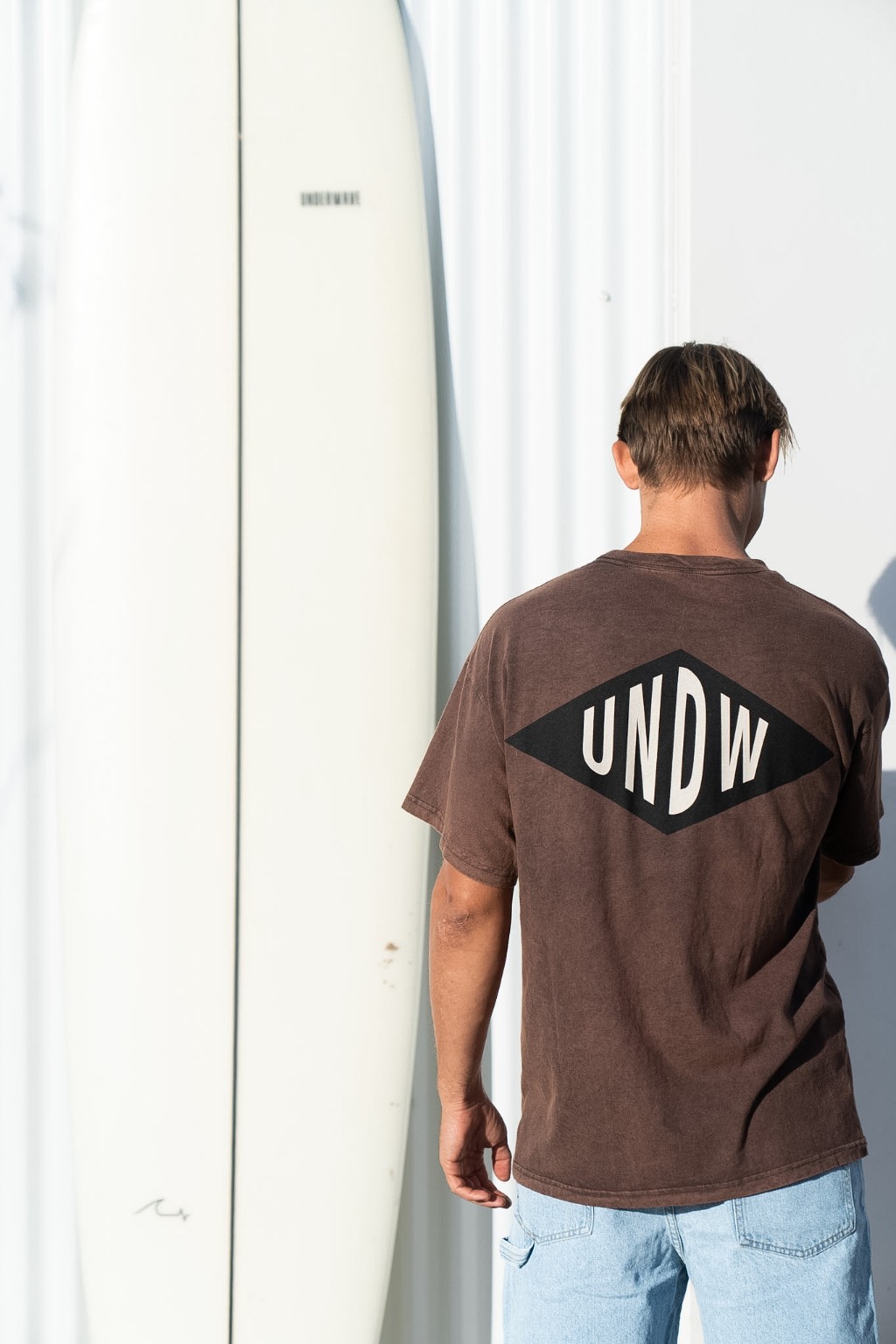 Chico de espaldas con una tabla de surf