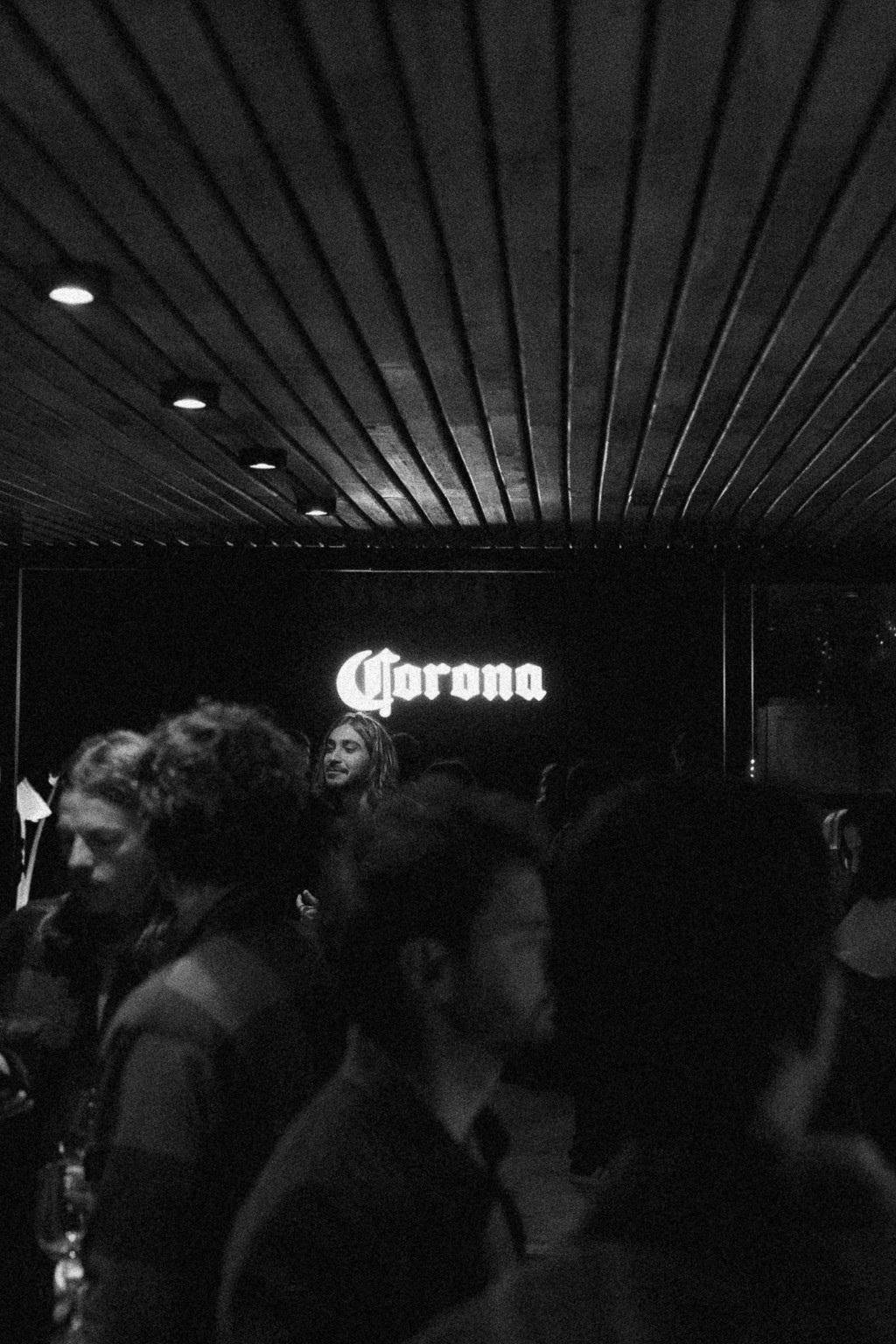 Gente frente al cartel de Corona, foto en blanco y negro