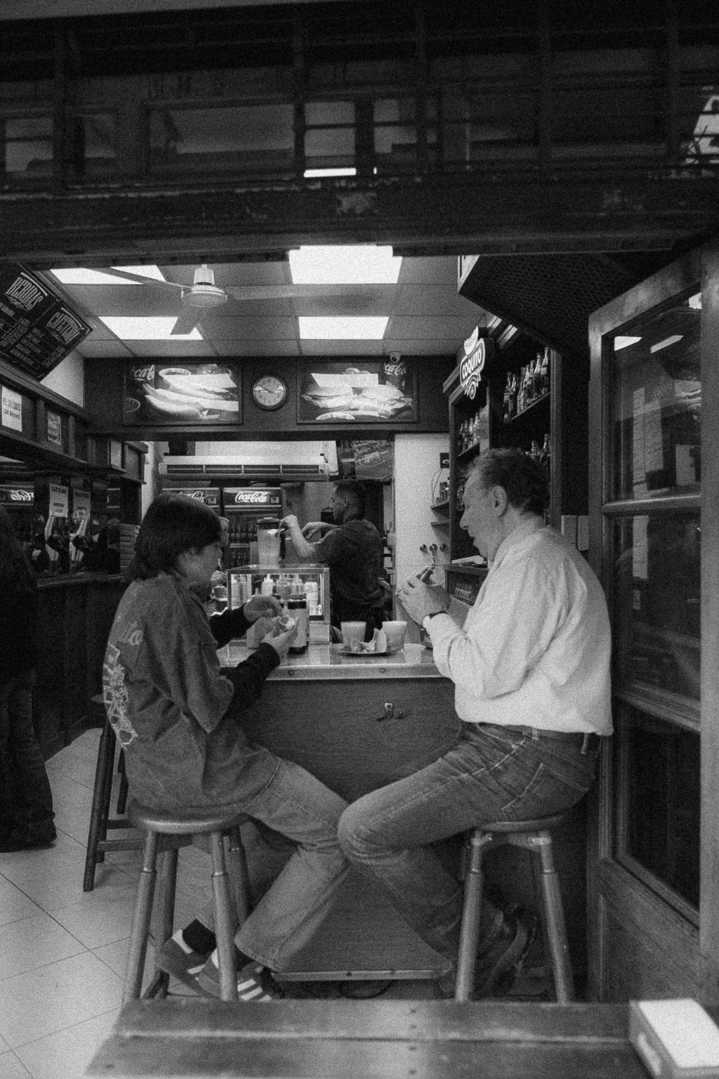 Un abuelo y su nieto comiendo un pancho en Coquito, foto en blanco y negro