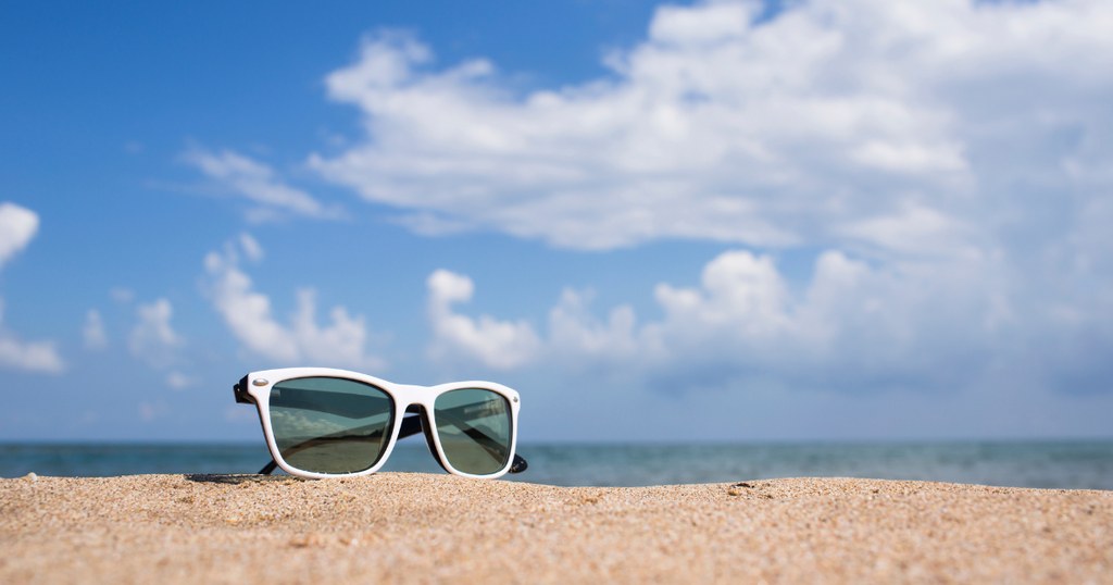 óculos de praia na areia com fundo do céu