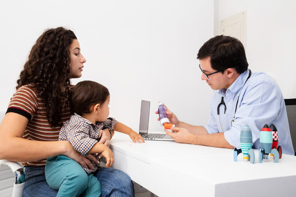 mãe no médico com criança que não quer tomar remédio